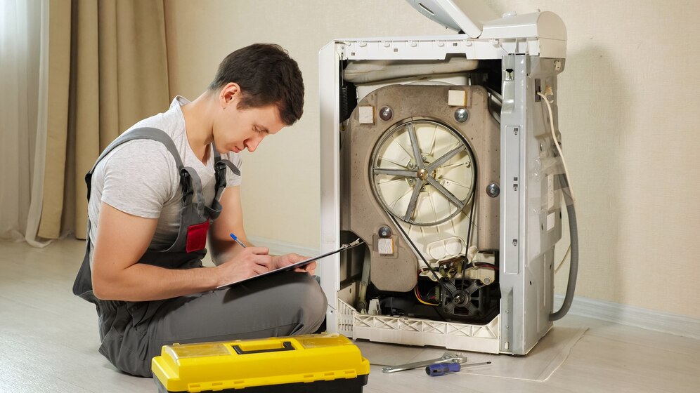 a man writing on a clipboard next to a washing machine from laundry rescue